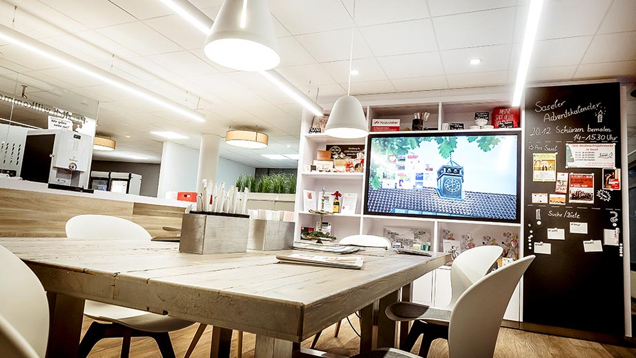 Ein moderner Besprechungsraum in einer Haspa Filiale mit einem digitalen Bildschirm an der Wand.